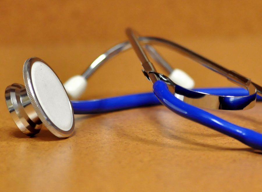 Photo features a blue stethoscope on a brown counter top.