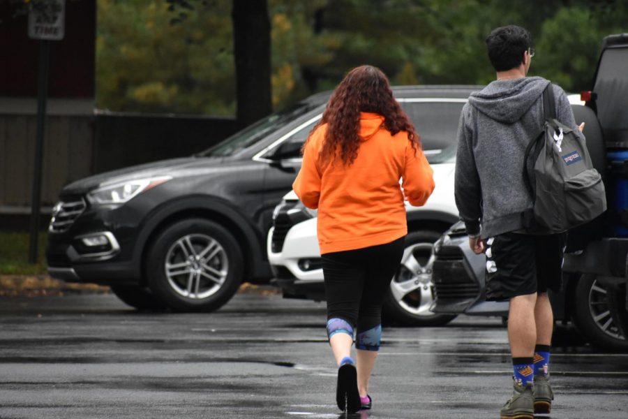 Commuter students Brianna Boggs and Cesar Corvera walk to their vehicles on a rainy day.