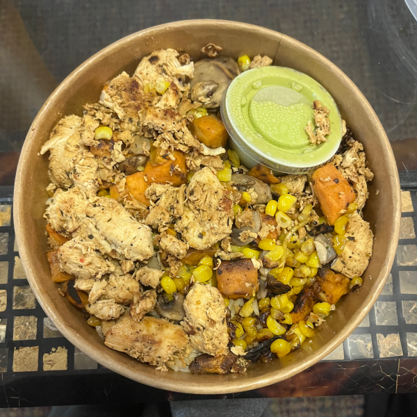 Photo by Lola Offenback. A bowl with quinoa, rice, chicken, sweet potato, corn, mushrooms, and an avocado ranch sauce.