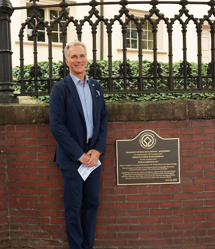 Photo by Lola Offenback. President Bryon Grigsby beside the newly unveiled commemorative Moravian Church Settlements plaque, located outside of Central Moravian Church. 
